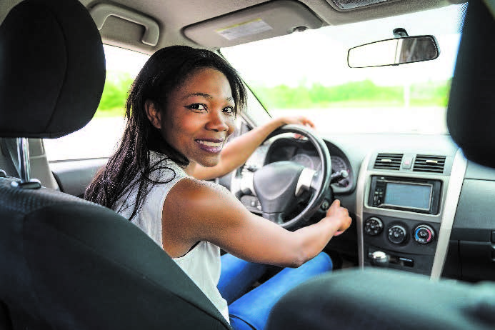 Woman smiling and seated in driver seat in car