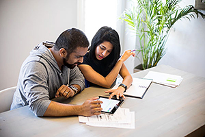 Husband and wife reviewing paper documents and using a tablet