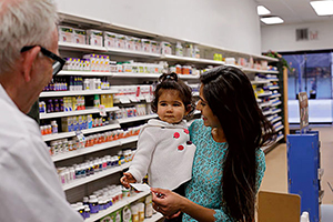 Mother holding her child at pharmacy counter