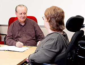 Woman in wheelchair speaking with a man at a meeting table