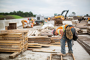 Construction works building bridge, with machinery in the background