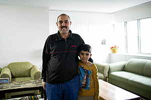 Syrian father and son standing in a living room