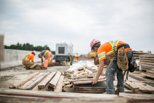 Construction worker lifting wood
