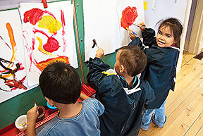 Trois enfants autochtones font de la peinture.
