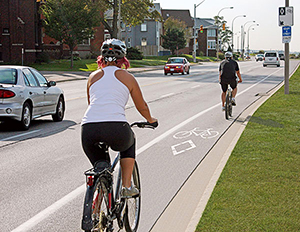 Deux cyclistes qui roulent sur une piste cyclable au bord d'une route