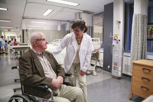 Un patient âgé en fauteuil roulant et une médecin dans un hôpital