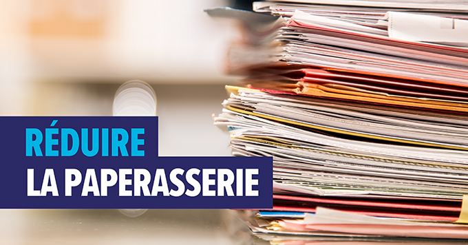 Photo d’une pile de papiers avec le texte suivant : Réduire la paperasserie