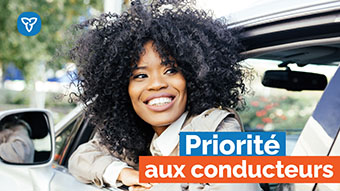 Photo d’une femme dans une voiture, avec le texte « Priorité aux conducteurs »