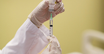 Photo of a healthcare worker holding a vaccine and a syringe