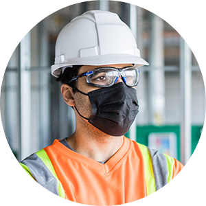 Photo d’un travailleur de la construction qui porte un casque de protection et un couvre-visage.