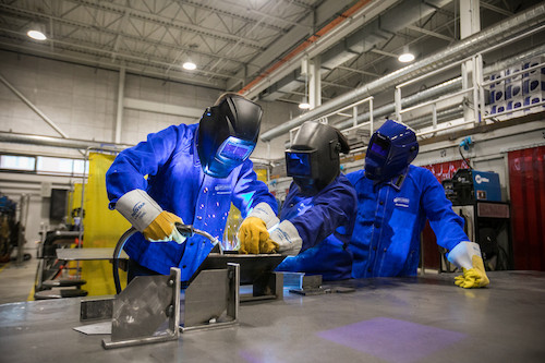 Image of three people working with metal.