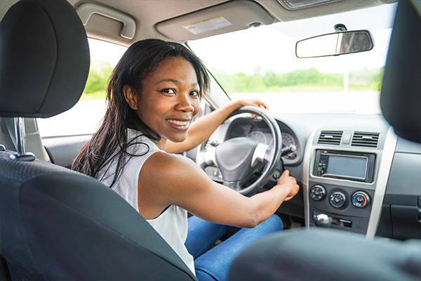 Femme souriante au volant d'une voiture.
