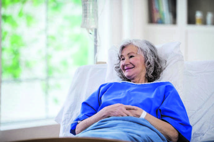 Patiente âgée souriante dans un lit d'hôpital.