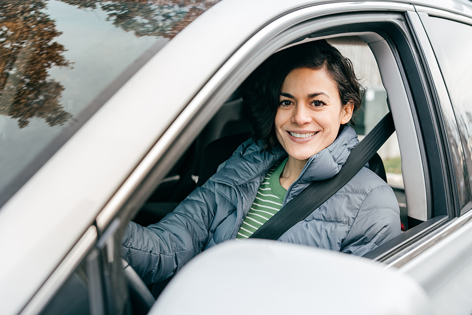 Photo of a woman sitting in driver's seat of a car smiling at the camera