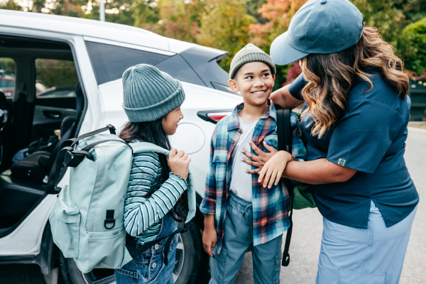 Photo d’une mère et de deux enfants près de leur voiture.