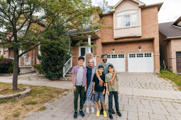 Photo d’une famille de cinq personnes à l’extérieur de leur foyer.
