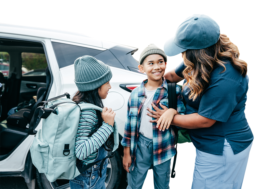 Photo of a parent and two children near their car.