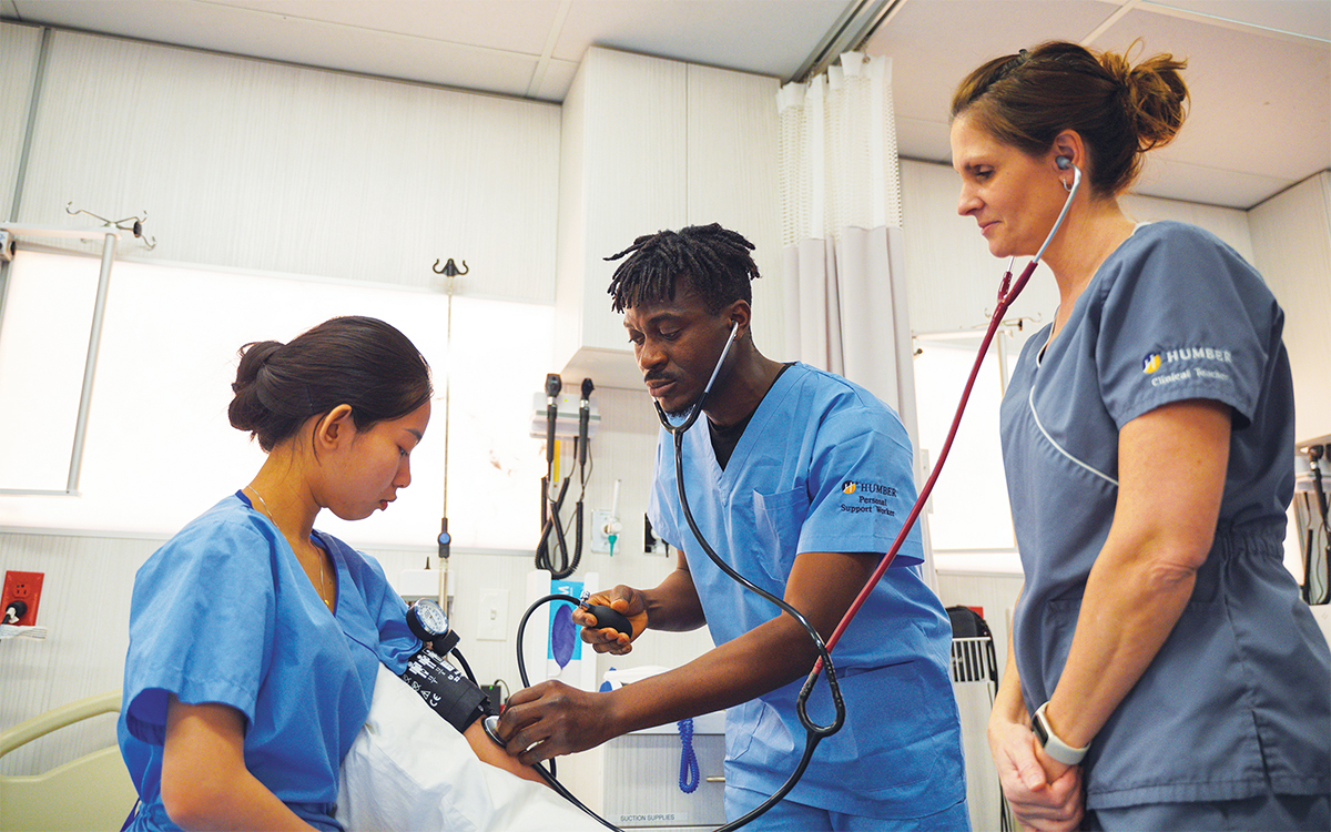 Photo d'étudiants en soins de santé, accompagnés d'une instructrice, procédant à une évaluation dans un environnement de formation clinique.